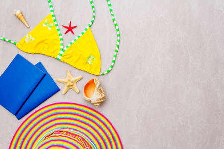 Summer travel and vacation concept. Sand background with swimsuit, hat, passports and seashells, top...