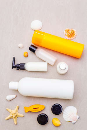 Summer travel and vacation concept. Sand background with cosmetics, seashells and artificial fish. Travel set of make up for the flight by plane, flat lay, top viewの写真素材