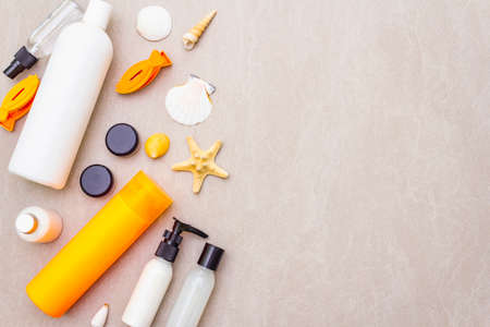 Summer travel and vacation concept. Sand background with cosmetics, seashells and artificial fish....