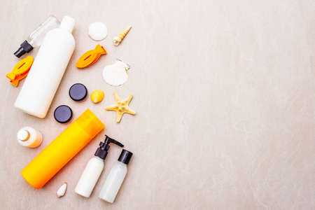 Summer travel and vacation concept. Sand background with cosmetics, seashells and artificial fish....