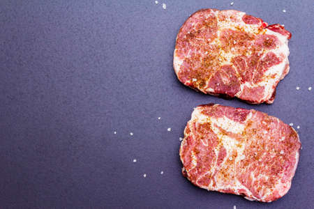 Organic raw pork steak, marinated in dry spices, with sea salt. Cooking animal protein concept. On a stone background, copy space, top view, close upの写真素材