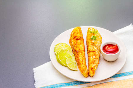 Grilled (fried) pollock in batter. On ceramic plate with lime, parsley and sauce. Cooking fresh...