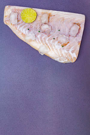 Frozen pollock fillet with pieces of ice. Concept of healthy seafood. Organic fish on a black stone...
