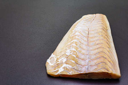 Fresh pollock fillet. Concept of healthy seafood. Organic fish on a black stone background, copy spaceの写真素材