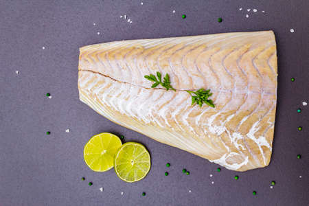 Fresh pollock fillet with lime, green pepper, salt and parsley. Concept of healthy seafood. Organic...