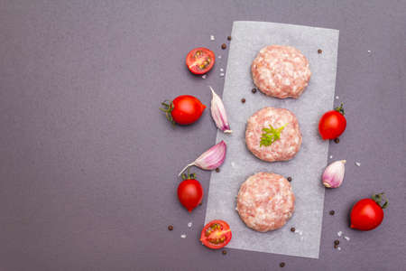 Raw fresh pork cutlets with spices and vegetables Healthy eating concept, animal proteins and vitamin. On a stone background, copy space, top viewの写真素材