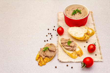 Chicken liver pate with butter. Crunchy baguette with flax and poppy seeds, fresh parsley. Concept of traditional french food. Vintage wooden board, linen napkin, on stone background, copy spaceの写真素材