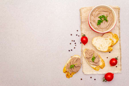 Chicken liver pate with butter. Crunchy baguette with flax and poppy seeds, fresh parsley. Concept of traditional french food. Vintage wooden board, linen napkin, stone background, top view copy spaceの写真素材