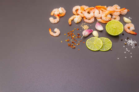 Fresh raw organic shrimps (prawns), spices, lime. Healthy vegetarian food concept. Black stone cooking background, copy spaceの写真素材