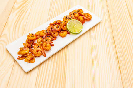 Fresh organic fried shrimp (prawns). Delicious seafood in teriyaki sauce with lime. On wooden boards background, copy space.の写真素材