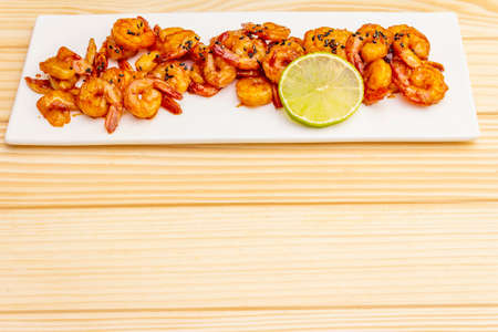 Fresh organic fried shrimp (prawns). Delicious seafood in teriyaki sauce with lime. On wooden boards background, copy space.の写真素材