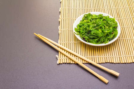 Traditional Japanese Hiyashi Wakame Chuka seaweed salad with sesame seeds. Healthy food concept isolated on stone background, copy space, close upの写真素材