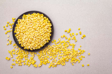 Frozen organic sweet corn. Healthy food concept, cooking background. In a plate on a stone...