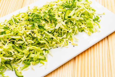 Fresh cabbage salad. Healthy vegan (vegetarian) food concept. Organic vegetables and sesame seeds, ceramic plate. On wooden background, close upの写真素材