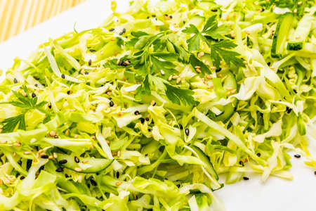 Fresh cabbage salad. Healthy vegan (vegetarian) food concept. Organic vegetables and sesame seeds, ceramic plate. On wooden background, close up, macroの写真素材