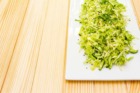 Fresh cabbage salad. Healthy vegan (vegetarian) food concept. Organic vegetables and sesame seeds, ceramic plate. On wooden background, copy spaceの写真素材