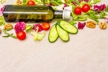 Vegan (vegetarian) healthy food concept. Fresh organic vegetables, walnuts and olive oil on stone cooking background, copy spaceの写真素材