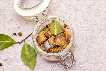 Slices of herring with spices in a glass jar. Mustard seeds, bay leaf, pepper mix. Healthy...