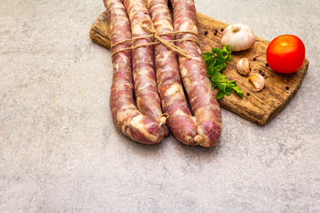 Raw pork sausage, fresh herbs and vegetables. Ingredient for cooking on the grill, picnic and homemade or restaurant food. On a stone background, copy spaceの写真素材