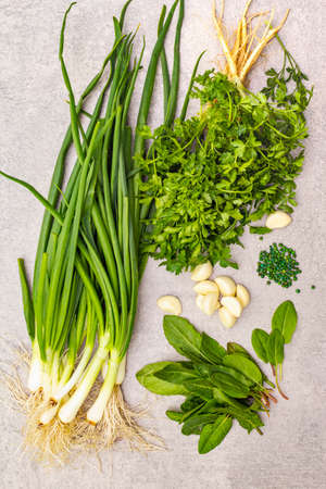 A bunch of fresh green onions, sorrel, parsley, garlic and green pepper peas. Healthy vegetarian (vegan) food concept, ingredients for cooking. On a stone background, close up, top viewの写真素材