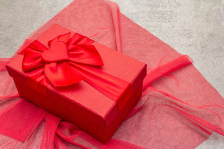 Romantic gift concept. Red box with bow and cloth. On a stone background, copy spaceの写真素材