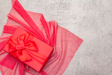 Romantic gift concept. Red box with bow and cloth. On a stone background, copy space, top viewの写真素材