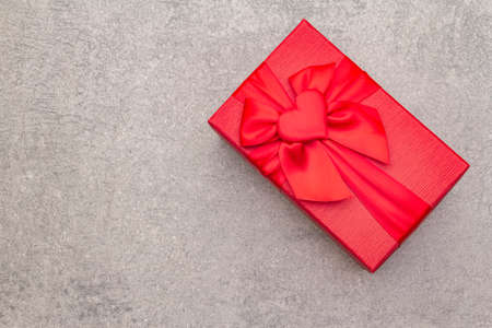 Romantic gift concept. Red box with bow on a stone background, copy space, top viewの写真素材