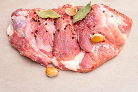 Raw pork shoulder with spices. Bay leaf, garlic. On a stone background, copy space, close upの写真素材