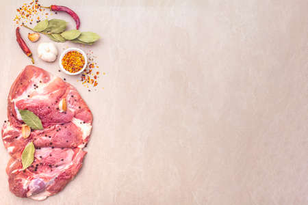 Raw pork shoulder with spices. Bay leaf, garlic. On a stone background, copy space, top viewの写真素材