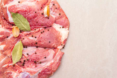 Raw pork shoulder with spices. Bay leaf, garlic. On a stone background, copy space, close upの写真素材