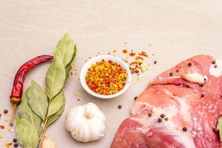 Raw pork shoulder with spices. Bay leaf, garlic. On a stone background, copy spaceの写真素材