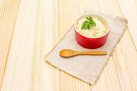 Warm mashed potatoes in a ceramic bowl with fresh parsley. On a vintage linen napkin on a wooden background, copy spaceの写真素材