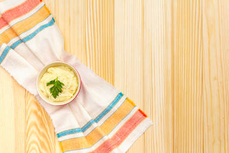 Warm mashed potatoes in a ceramic bowl with fresh parsley. On a vintage linen napkin on a wooden background, top view, copy spaceの写真素材