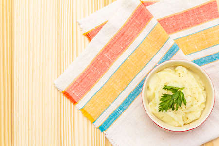 Warm mashed potatoes in a ceramic bowl with fresh parsley. On a vintage linen napkin on a wooden background, copy space, top view, close upの写真素材