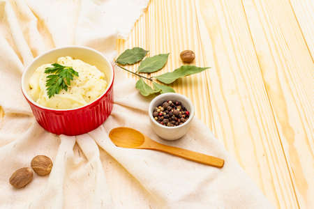 Warm mashed potatoes in a ceramic bowl with fresh parsley and dry spices and herbs. On a vintage linen napkin on a wooden background, copy spaceの写真素材