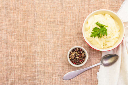 Warm mashed potatoes in a ceramic bowl with fresh parsley and dry pepper mix. On a linen cloth background, copy space, top view, close upの写真素材
