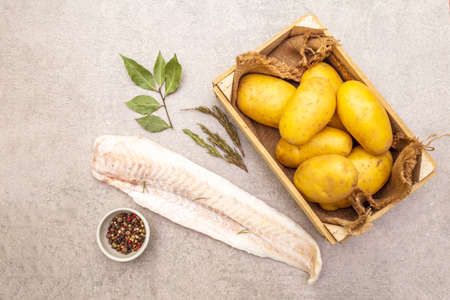 Raw young potatoes and frozen hake fillets. Ingredients for fish and chips. Spices and herbs on a...