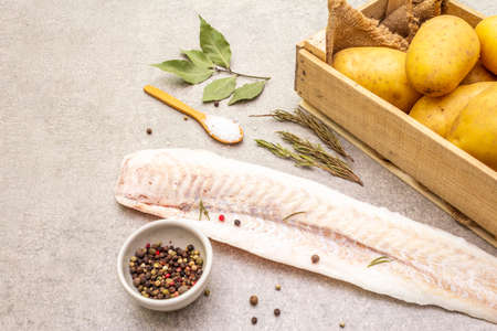 Raw young potatoes and frozen hake fillets. Ingredients for fish and chips. Spices and herbs on a...