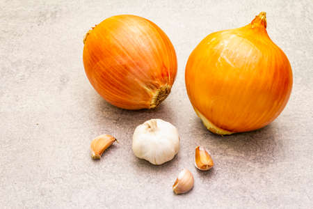 Giant onion bulbs with garlic for scale on a stone background. Food cooking background, close upの写真素材