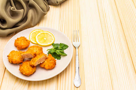 Homemade red fish cakes with lemon and parsley in ceramic plate. With fabric drapery and fork on wooden background, copy spaceの写真素材