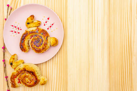 Fresh bun in the form of an Easter bunny. The concept of children's holiday bakery. In pink ceramic...