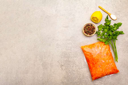 Raw minced red fish (stuffing) on a stone background. Ingredient for making fish-balls, casseroles, terrine, pate. Spices, salt, parsley, lemon. On a stone background, top view, copy spaceの写真素材