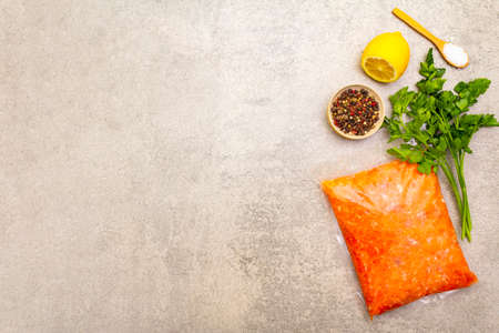 Raw minced red fish (stuffing) on a stone background. Ingredient for making fish-balls, casseroles, terrine, pate. Spices, salt, parsley, lemon. On a stone background, top view, copy spaceの写真素材