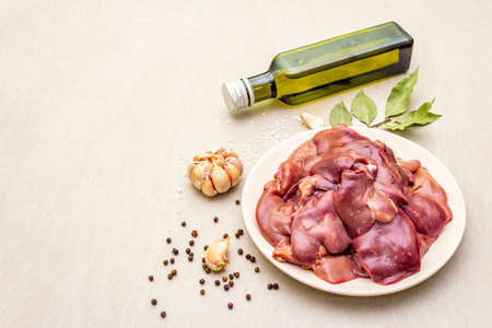 Raw chicken liver with spices on a stone background. Garlic, olive oil, black pepper, bay leafの写真素材
