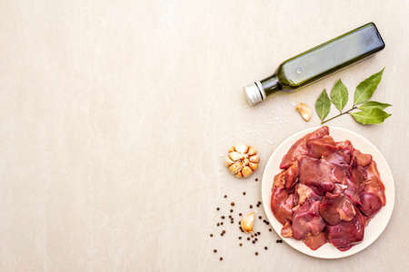Raw chicken liver with spices on a stone background. Garlic, olive oil, black pepper, bay leaf, top view, copy spaceの写真素材