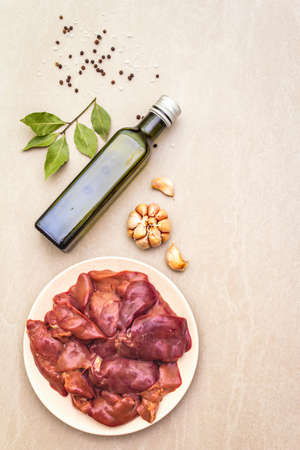 Raw chicken liver with spices on a stone background. Garlic, olive oil, black pepper, bay leaf, top viewの写真素材