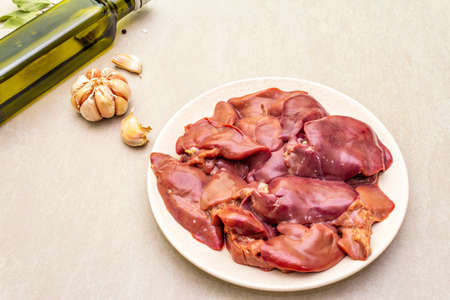 Raw chicken liver with spices on a stone background. Garlic, olive oil, black pepper, bay leaf, close upの写真素材