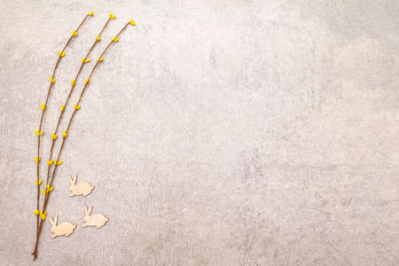 Artificial decorative willow twigs and wooden figures of bunny. The concept of Easter cards, wallpapers, stone background. Top view, copy spaceの写真素材