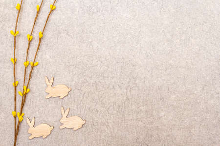 Artificial decorative willow twigs and wooden figures of bunny. The concept of Easter cards, wallpapers, stone background. Top view, copy spaceの写真素材