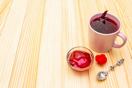 Karkade tea from hibiscus petals (Sudanese rose). Gentle romantic breakfast concept. On a wooden background, copy spaceの写真素材